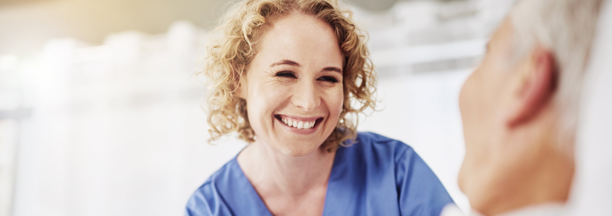 Pflegefachfrau der Caritas München lächelt Patienten freundlich an | © Cecilie Arcurs/Getty Images iStock 610435464