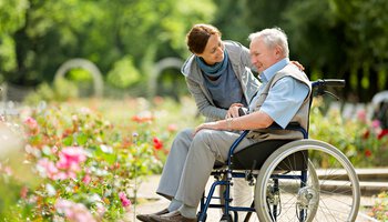 Seniorenbetreuung Jobs - Pflegerin und Rollstuhlfahrer lachend in einem Park | © Fred Froese/Getty Images iStock 599257344