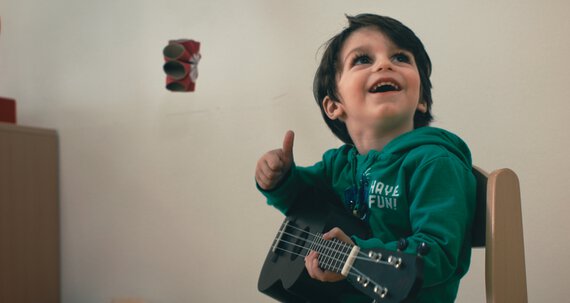 Erziehung - kleiner Junge spielt Gitarre | © Caritas München